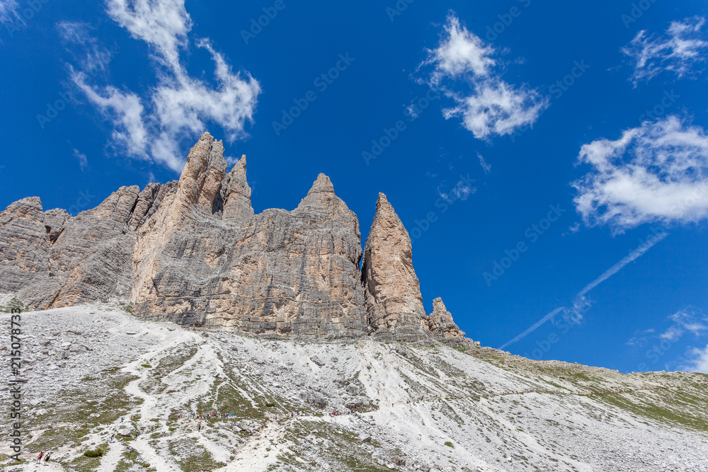 Column of tourists walking at the foot of the Tre Cime di Lavaredo, Dolomites, Italy