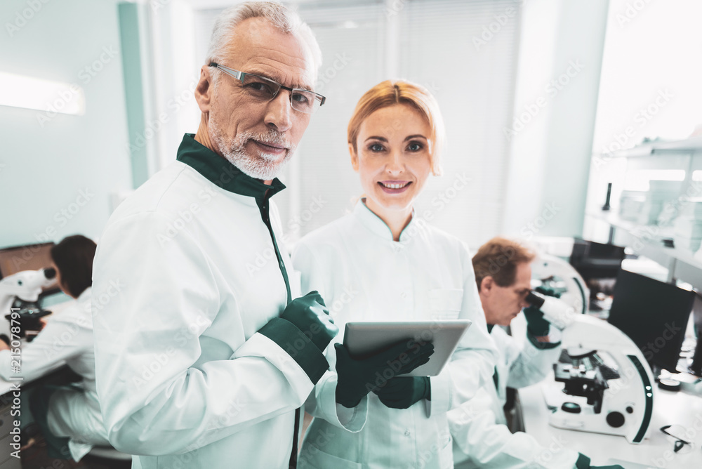 Working process. Smiling successful scientists feeling satisfied while enjoying working process in modern laboratory Working process. Smiling successful scientists feeling satisfied while enjoying working process in modern laboratory