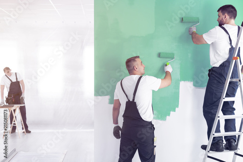 фотографія Workers painting wall on green while standing on ladder while finishing interior