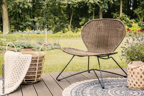 Close-up of a brown garden chair and a beige blanket in a basket on a wooden patio in the yard