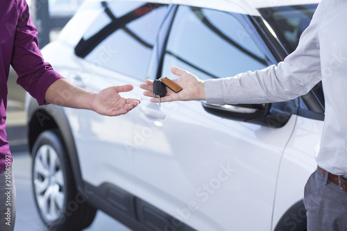 Close-up of car seller's hand with keys and buyer after transaction in the salon