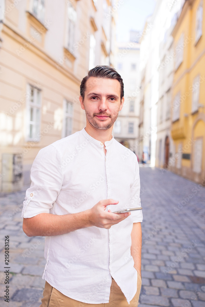 Obraz premium Man tourist with cellphone in Europe street. Caucasian boy looking at camera outdoor