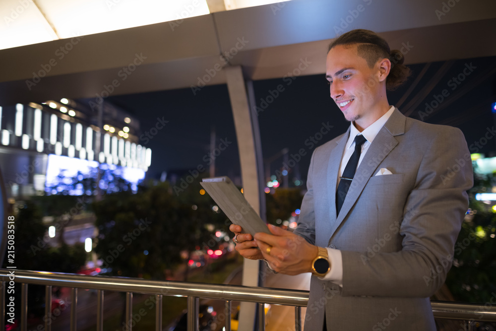 Fototapeta premium Young Handsome Businessman Outdoors At Night Using Digital Tablet