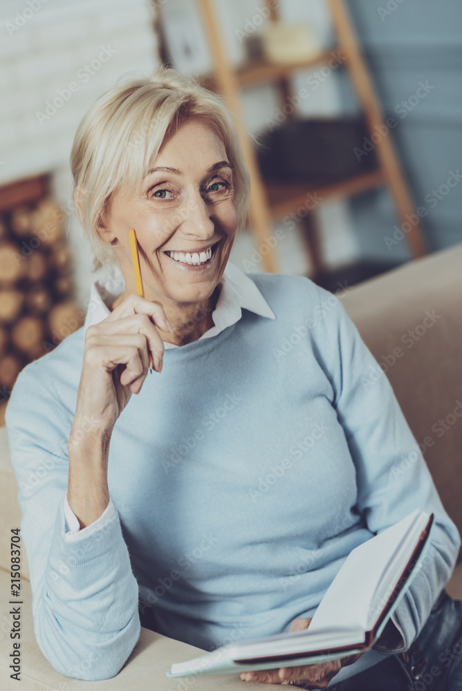 Obraz premium Enjoy your weekend. Cheerful retirement keeping smile on her face while holding her notebook in left hand
