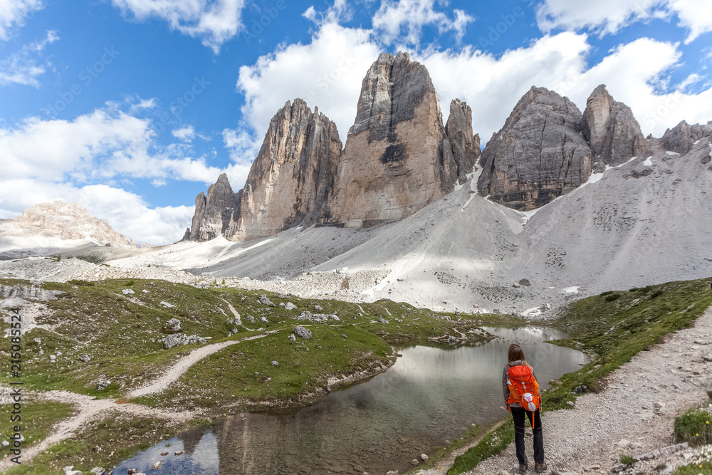 Girl watching a beautiful alpine lake with the reflections of the Tre Cime di Lavaredo, Dolomites, Italy