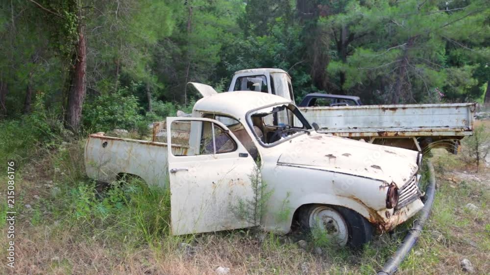 Closeup view of old rusty abandoned cars with peeling paint standing in wood outdoors. Real time full hd video footage. Closeup view of old rusty abandoned cars with peeling paint standing in wood outdoors. Real time full hd video footage.