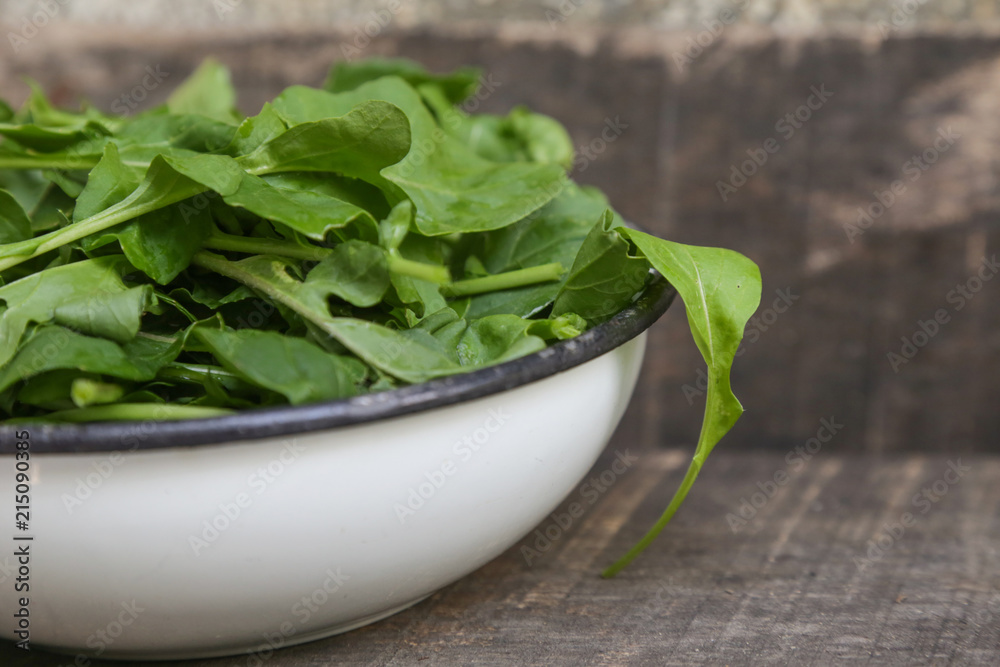Fresh rucola salad in a bowl on the wooden background Fresh rucola salad in a bowl on the wooden background