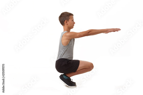 Teen in a T-shirt and shorts performs gymnastic exercises.