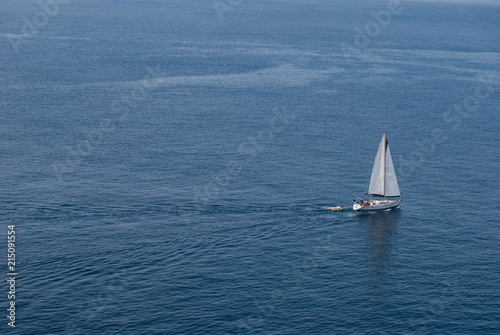 Sailboat sailing in the endless blue and quiet sea