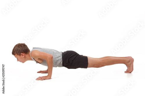 Teen in a T-shirt and shorts performs gymnastic exercises.
