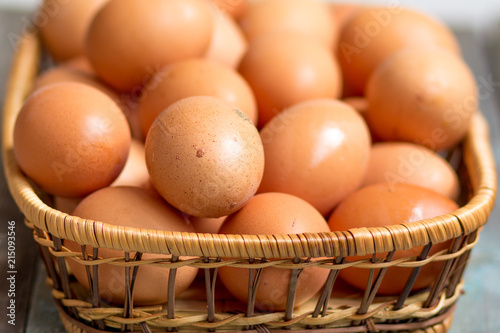 Brown farmers cage-free chicken eggs in basket, close up, rustic table