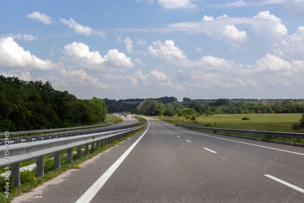 Almost emty asphalt highway with blue cloudys sky on background. Toll roads construction