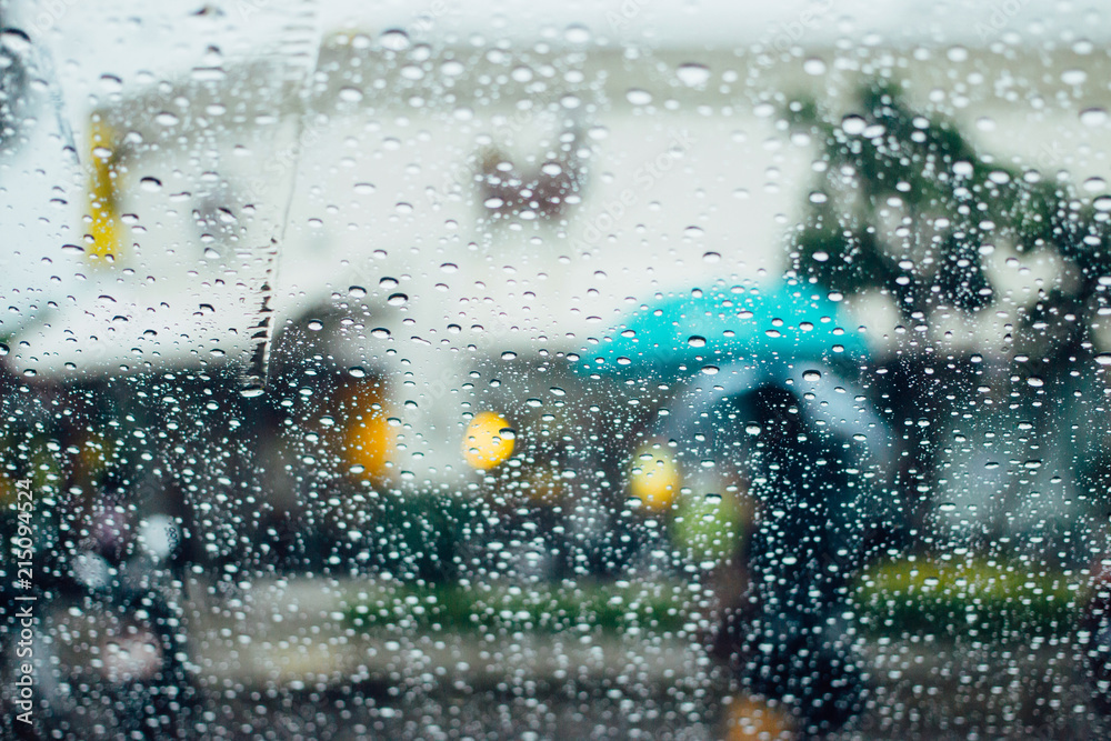 Rain on a window looking out to people in a street scene in Thailand