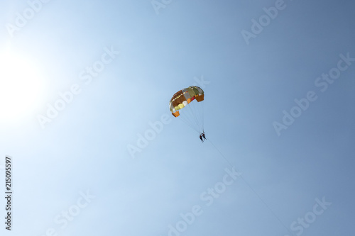People on a parachute against the blue sky.