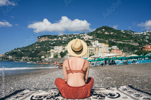 Fototapeta Naklejka Na Ścianę i Meble -  girl sits on the beach looking at the mountains Italy Amalfi