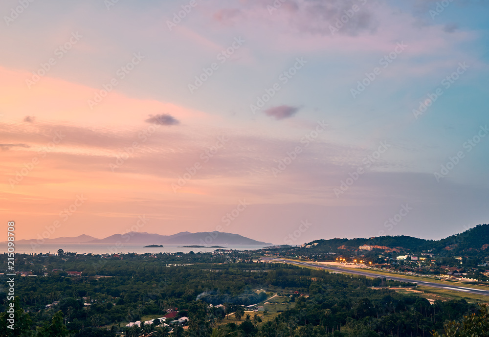 Colourful sunset over airport, mountains and forest on a tropical island      