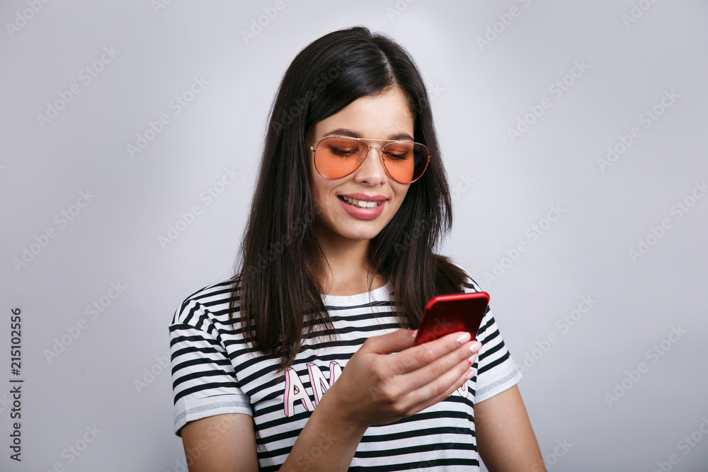 Young beautiful happy woman using smart phone. Isolated on grey background Young beautiful happy woman using smart phone. Isolated on grey background