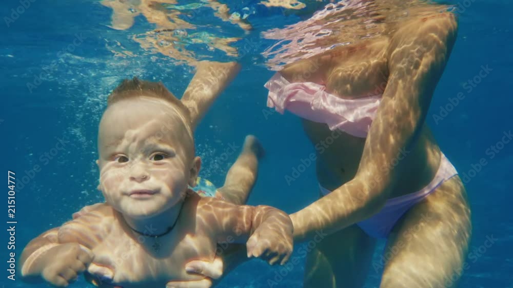 The baby boy dives in the pool. Underwater video. Slow motion 10 bit video