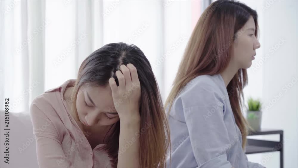 Unhappy Asian lesbian lgbt couple sitting each side of sofa with moody emotion in living room. Women conflict with her girlfriend and have bad relationship at home. Unhappy Asian lesbian lgbt couple sitting each side of sofa with moody emotion in living room. Women conflict with her girlfriend and have bad relationship at home.
