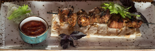 Food and leisure concept - shashlik on a barbecue skewer with sauce photo