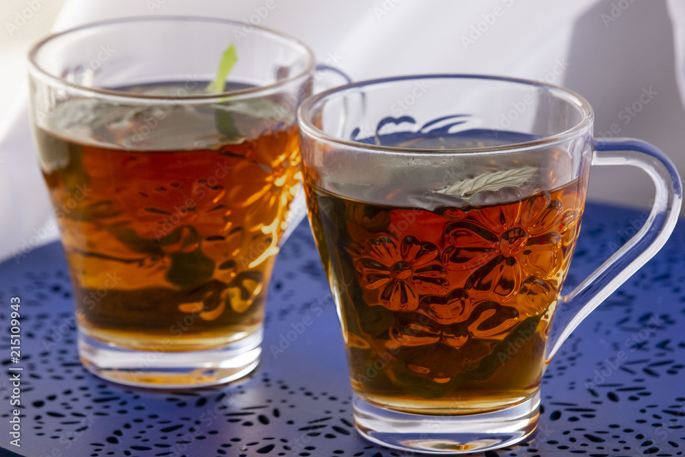 Two glasses of tea with fresh mint on the blue table Two glasses of tea with fresh mint on the blue table