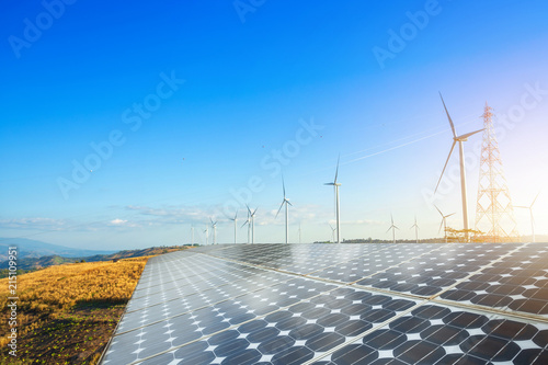 solar panels with wind turbines against mountanis landscape against blue sky with clouds,Alternative energy concept,Clean energy,Green energy.