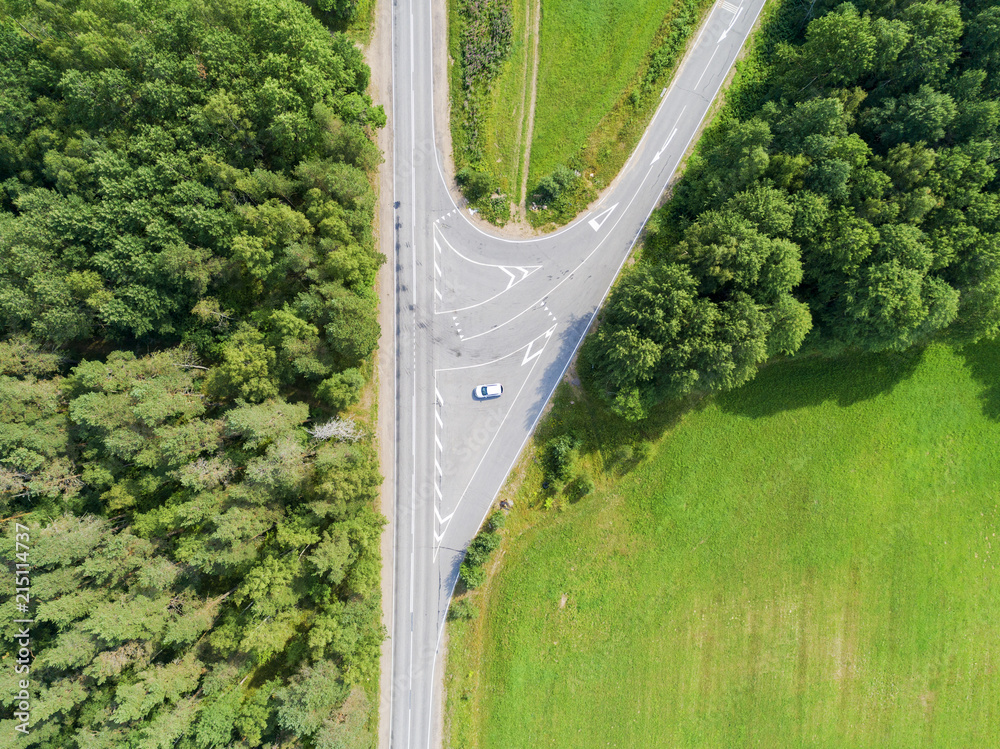 Aerial view of highway. Aerial view of a country road with moving car. Car passing by. Aerial road. Aerial view flying. Captured from above with a drone. - obrazy, fototapety, plakaty 