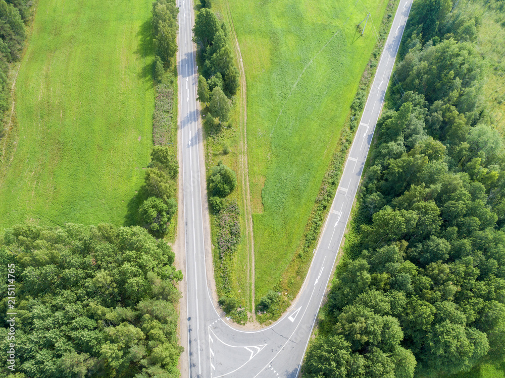 Aerial view of highway. Aerial view of a country road. Car passing by. Aerial road. Aerial view flying. Captured from above with a drone. - obrazy, fototapety, plakaty 