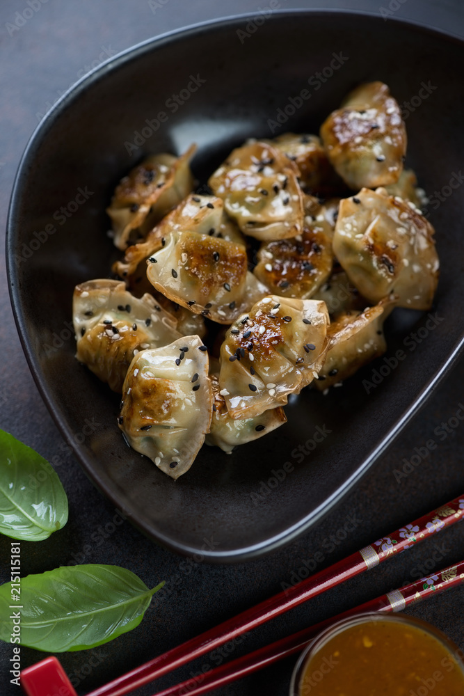 Close-up of a black bowl with fried korean wontons, studio shot, selective focus