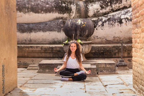 Young girl meditating in yoga position in a Buddhist temple photo