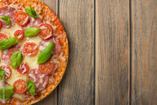 Pizza margarita on a wooden background, top view. Pizza Margarita with tomatoes, basil and Mozzarella cheese.