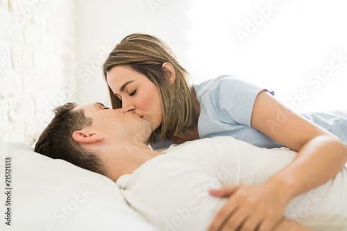 Female Kissing Man On Mouth While Reclining In Bed
