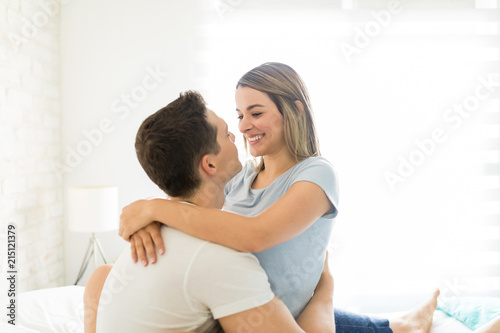 Couple Romancing While Sitting On Bed