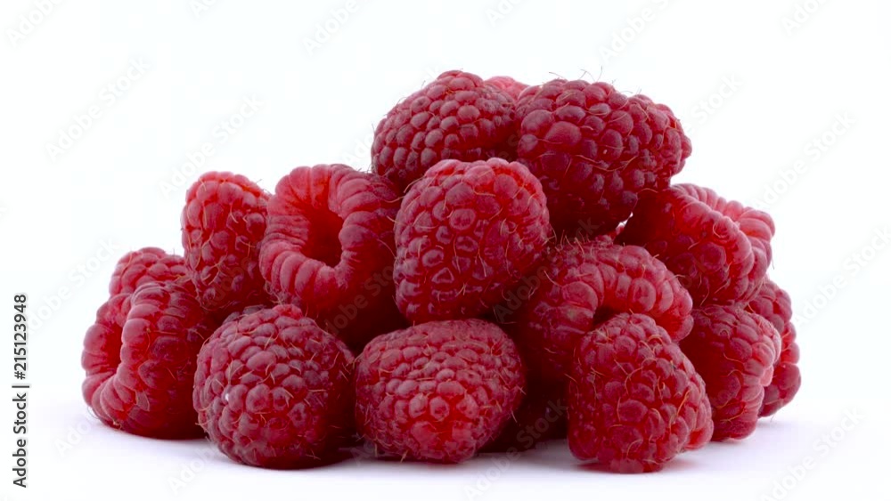 Heap of raspberries are rotated on the on the turntable isolated on the white background. Close up. Side view. Heap of raspberries are rotated on the on the turntable isolated on the white background. Close up. Side view.