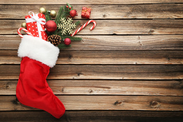 Red stocking with fir-tree branches and christmas decorations on wooden table