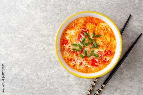 Fotografie Traditional chinese egg drop soup with tomato and green onion in bowl on gray st