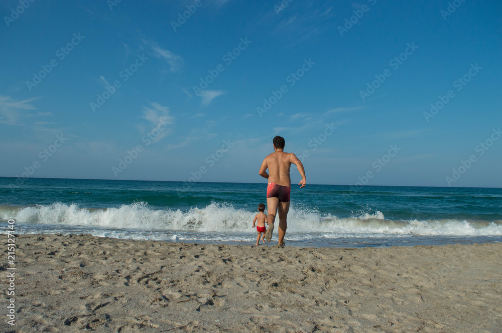 father runs after his son. the child rushes to the sea. 