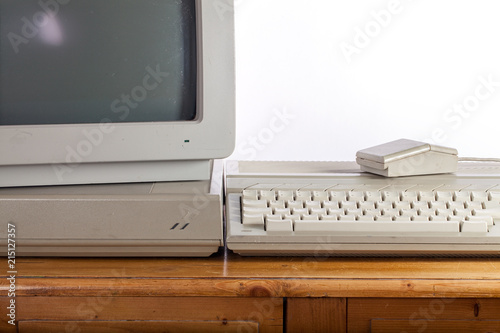 Dirty retro computer system on old pine desk. Outdated computing and vintage technologies. photo