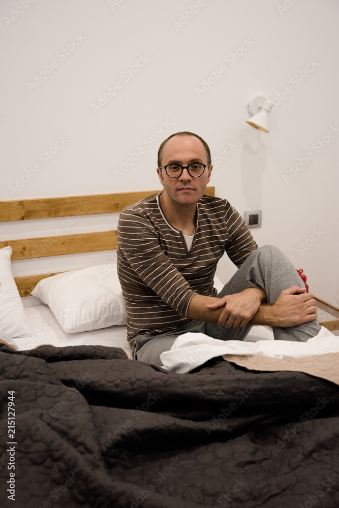 Fototapeta premium Man sitting on a bed in the bedroon