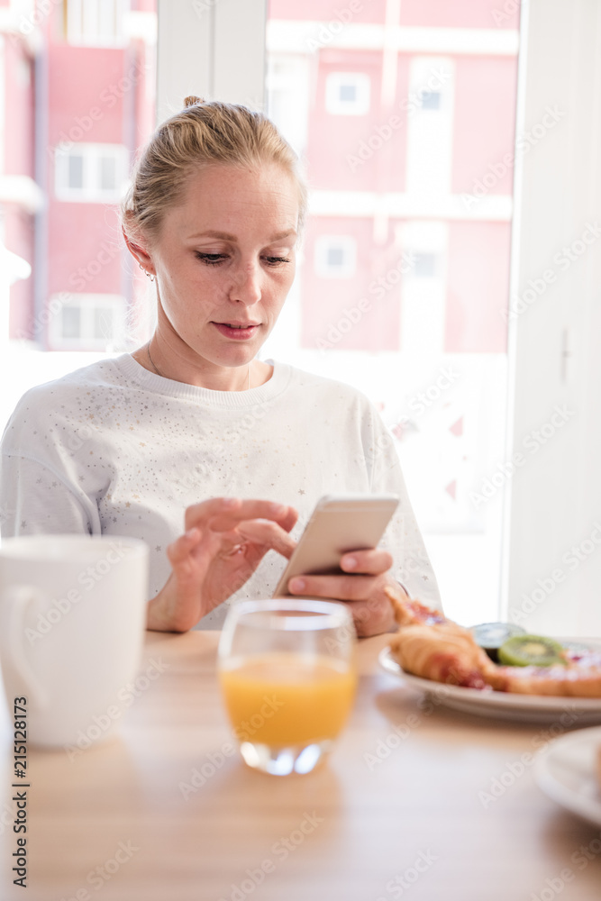 Woman at a table texting from a cell phone