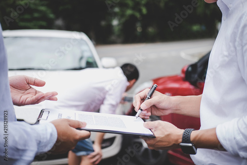 Insurance Agent examine Damaged Car and customer filing signature on Report Claim Form process after accident, Traffic Accident and insurance concept