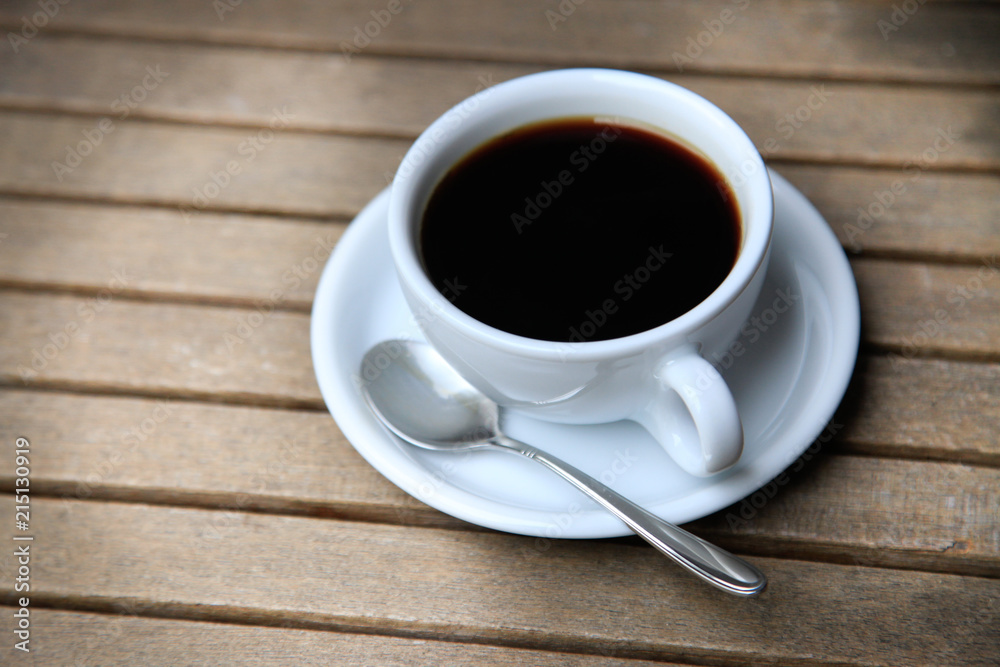 White cup with brown coffee on a wooden table.