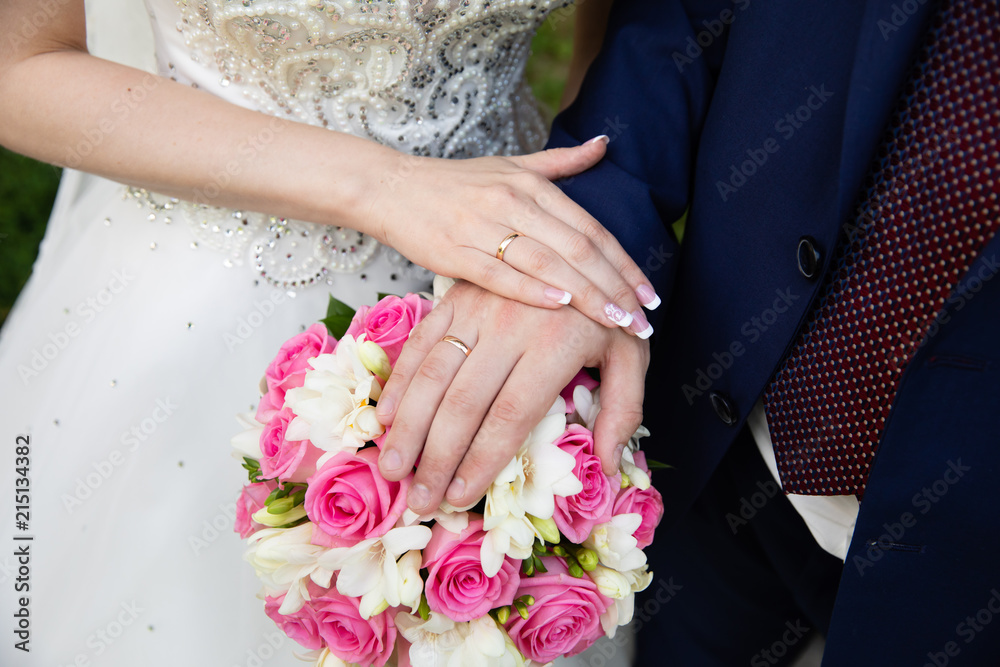 Hands of the groom and bride with rings and bridal bouquet Hands of the groom and bride with rings and bridal bouquet