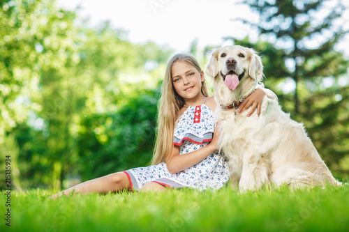 Little girl with golden retriever dog in the park