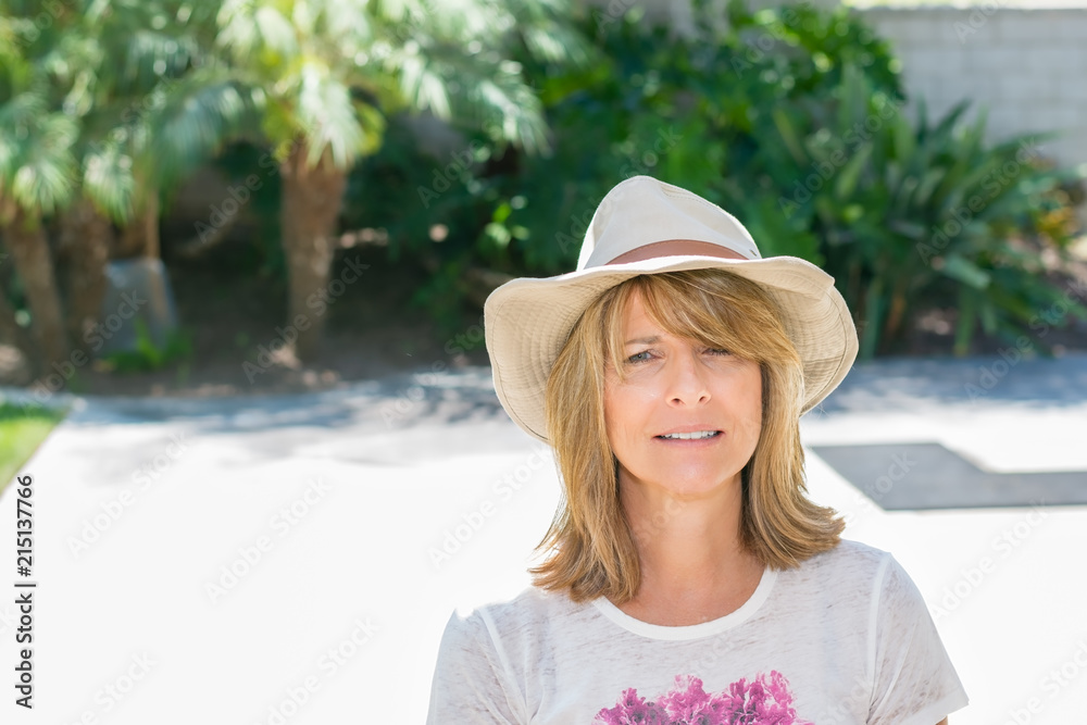 Beautiful woman smiles wearing cowboy hat on patio in bright sunshine