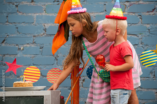 Happy Brothers-boys in colored clothes and girl celebrate birthday of youngest boy on pirate ship. Girl and boy are dressed in carnival hat for parties. Children are happy together. 3 years old photo
