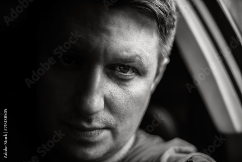 Portrait of a man in a car close-up in black and white tones. Monochrome photo.