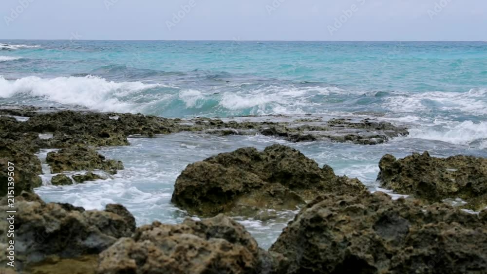 Breaking waves beating and rolling stones at sea coast Breaking waves beating and rolling stones at sea coast