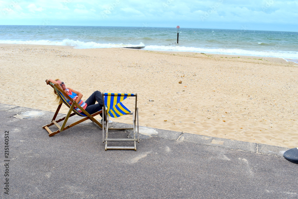 Blond girl chilling on a deck chair on the Bournemouth beach, England Blond girl chilling on a deck chair on the Bournemouth beach, England