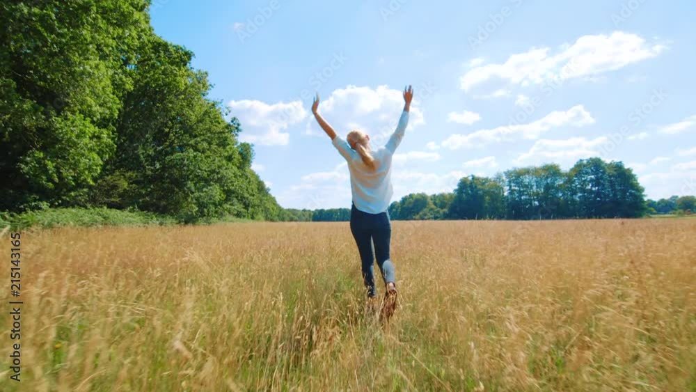 Young blond woman running through long grass in a field waving her arms in the air without a care in the world. Drenthe, The Netherlands. Young blond woman running through long grass in a field waving her arms in the air without a care in the world. Drenthe, The Netherlands.